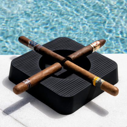 Three cigars on a black ashtray by a pool